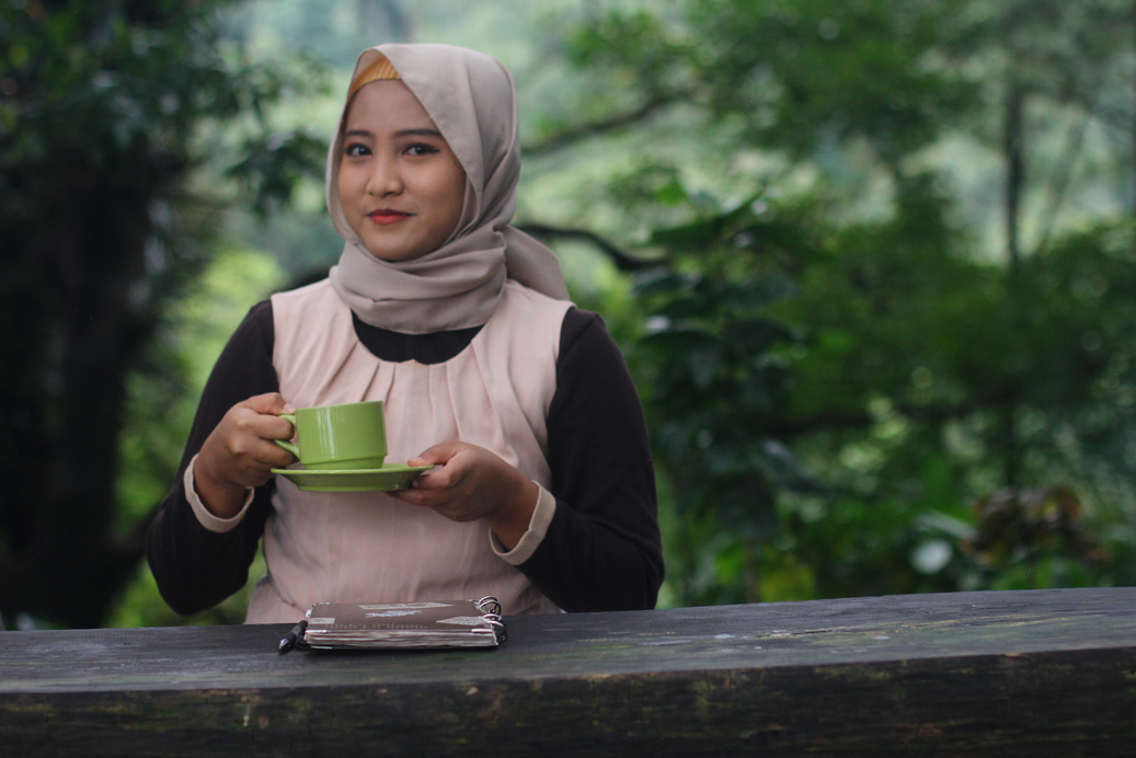 perempuan hijab meminum kopi di hutan alam